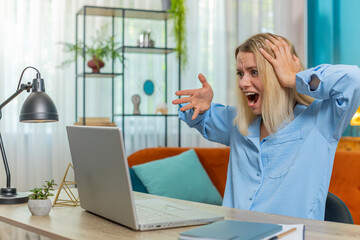 Displeased sad businesswoman using laptop notebook typing browsing working loses becoming surprised...
