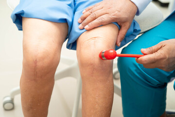 Obraz premium Asian doctor knock on knee reflex nerve for check and treatment senior patient in hospital.