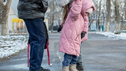 Grandfather walks with his granddaughters after school in the park in sunny winter day