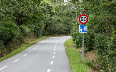 Un panneau de limitation de vitesse indiquant 50 km/h le long d'une route. Un autre panneau signale...