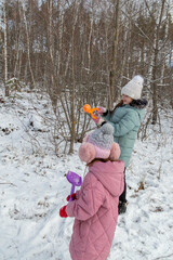 Little girls with her grandfather walk in a snowy forest, have fun together