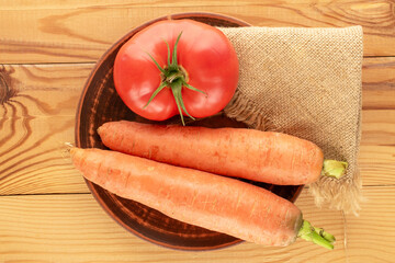 Organic carrots and tomatoes on a wooden table, macro, top view.