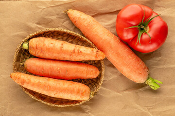 Organic carrots and tomatoes on kraft paper, macro, top view.