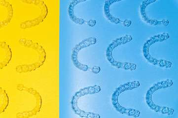 Invisible transparent brackets or parentheses on blue yellow background lie in a pattern, top view