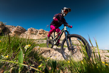 Mountain biker riding down a grassy slope. Enduro mountain bike. MTB against a mountain landscape