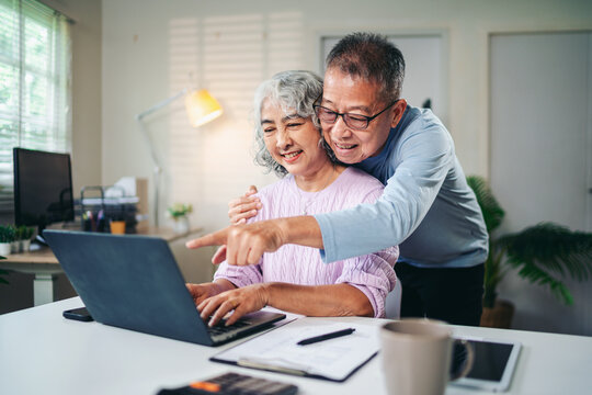Senior Asian Couple Enjoying Retirement Planning Online Together at Home Using Laptop Computer Searching for Investment Ideas and Financial Security