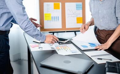 Two business colleagues pointing on document chart to brainstorming about new startup project and putting post it notes