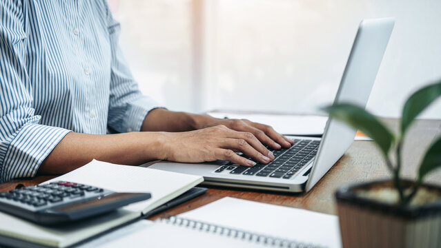 Business woman reading financial report to analysis investment of new business and typing information on laptop - Powered by Adobe