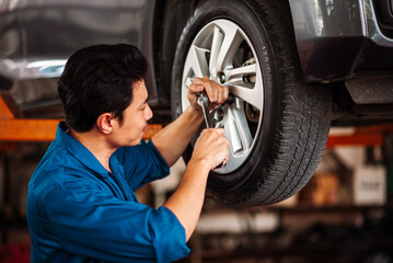 Garage Worker Tightening Wheel Nuts, Professional Auto Technician Performing Tire Check and Car...