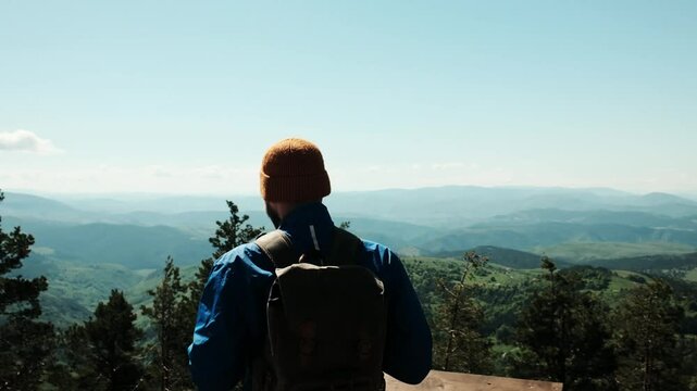 Male hiker with raised arms celebrating at the summit of Tornik mountain in Zlatibor, Serbia, under a bright blue spring sky. Solo travel concept. Horizontal 4k footage