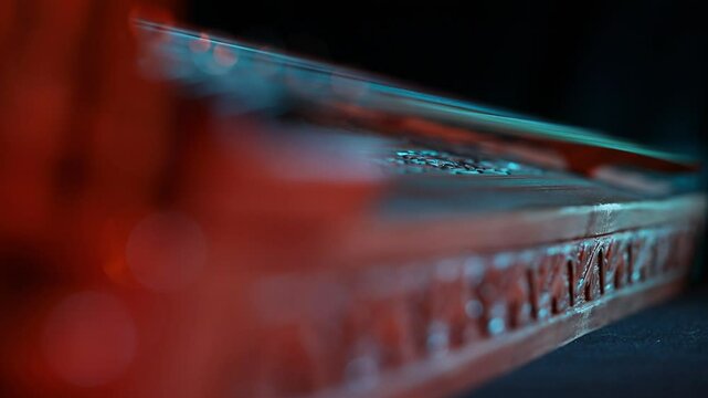 Cinematic macro close-up of a traditional wooden stringed instrument. Slow focus pull along tuning pegs and strings under dramatic red and teal lights, creating a moody atmosphere.