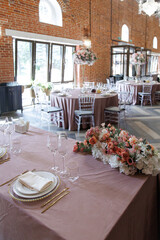 Elegant wedding reception setting in a brick venue featuring round tables with floral centerpieces and exquisite place settings. The warm atmosphere reflects sophistication and style.