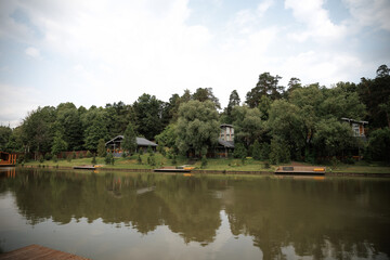 Peaceful lakeside scene with charming cottages nestled among lush greenery. The tranquil setting...
