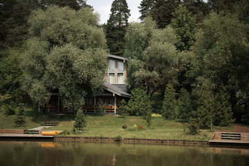 Peaceful lakeside scene with charming cottages nestled among lush greenery. The tranquil setting...