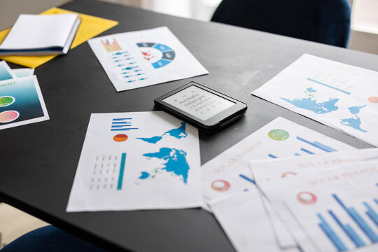 E reader laying on desk showing nonsense text surrounded by business charts and graphs
