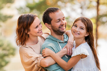 Fototapeta premium Happy family portrait with man, woman and girl bonding in nature.