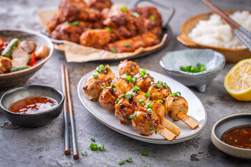 Assortment of Asian street food, stir fry with vegetables, chicken wings, meat balls and rice