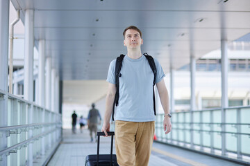 駅の通路を笑顔で歩く男性旅行者