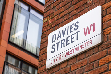 Obraz premium Davies Street W1 road sign on red brick wall in Mayfair, City of Westminster, London