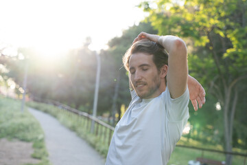 Man stretching muscles in park at sunset