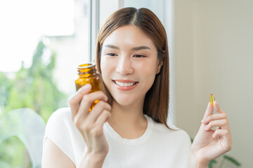 Dietary supplement concept, happy asian young woman hand holding fish oil pills, drugs medical...