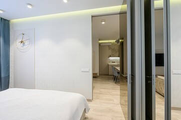 bright, modern apartment with a partial view of the bedroom, a glimpse into the kitchen, and mirrored closet doors