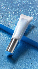 Glitter gloss product tube on sparkling blue background with shiny silver cap, cosmetic container for beauty care