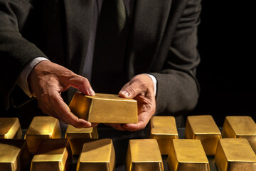 Hands of a banker or businessman, bank vault manager holding a gold bar, gold holdings concept. Savings and investments, business and finance
