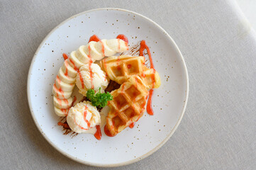 tasty dessert. Top view of Croffle serve with ice cream, banana and topping with strawberry syrup.
