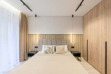 modern bedroom features a neutral palette with a bed, wood accents, bedside tables, and ambient lighting. Minimalist decor