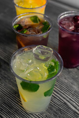 a set of colorful summer cocktails with berries, mint leaves and ice cubes on a gray background. summer menu for coffee shops and cafes