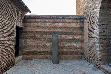 Single ancient column stands in a quiet courtyard of the Alcazaba, surrounded by historic brick walls and timeless silence.