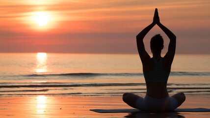 Woman in yoga pose at sunset on beach with hands raised in prayer position silhouette meditation