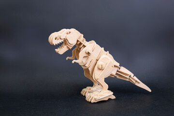 Dinosaur wooden puzzle isolated on dark background, with copy negative space