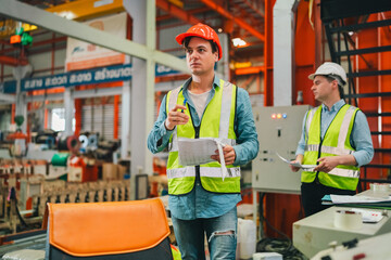 Engineers in high-visibility vests inspecting industrial control systems in modern factory,...