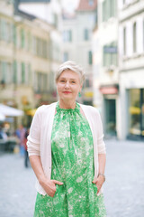 Outdoor portrait of beautiful 55 -60 year old woman posing with city background, fashion and helthy lifestyle