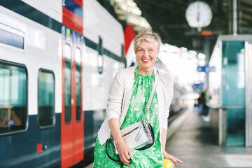 Outdoor portrait of 55 - 60 year old woman at the train station, vacation and active lifestyle