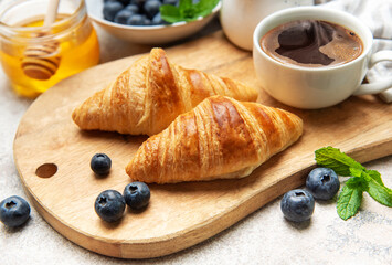 Delicious french croissants with coffee, honey and fresh blueberries for breakfast