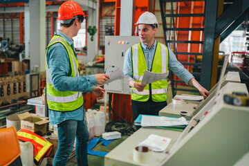 Engineers in high-visibility vests inspecting industrial control systems in modern factory,...