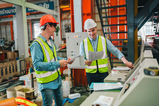 Engineers in high-visibility vests inspecting industrial control systems in modern factory, ensuring automation robotics, intelligent operations run under safety protocols, technical supervision