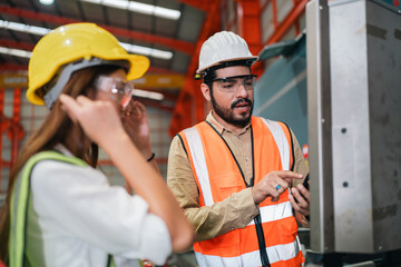 Industrial technicians collaborate in factory, focusing production systems, equipment operation,...