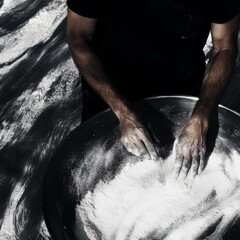 A man is making a dough with his hands in a bowl