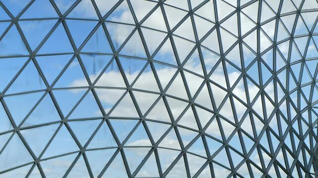 Building with a lot of glass windows and a blue sky in the background. The building has a lot of triangles and the sky is clear