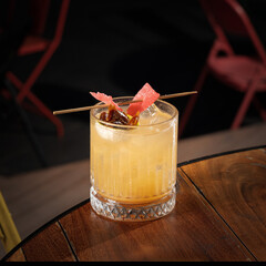 Whiskey based cocktail in a whiskey glass with red colour, garnish and ice cubes