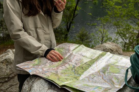 Young woman studying a map of Tatra National Park, planning hiking routes in the Tatra Mountains near Zakopane, Poland, preparing for outdoor travel and exploration