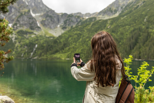 girl takes a photo of mountains on smartphone, hiking in the mountains in summer, outdoor recreation
