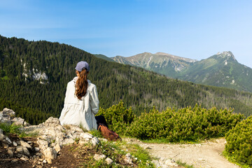 girl tourist sits on the edge of a cliff enjoying the view of the mountains and valley. travel and hiking in the mountains, Tatra Mountains, Poland