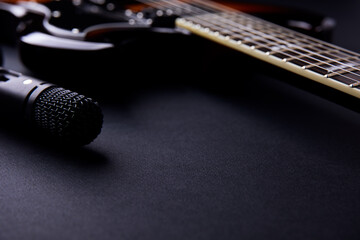 Microphone and electric guitar on a dark background.	