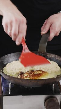 Raw potato mixture for draniki is placed onto a hot frying pan for cooking.