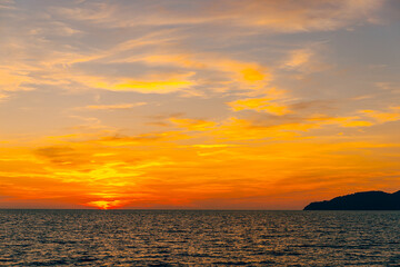 Front view in the blue ocean in the evening, the sun was setting, reflections fell on the smooth calm surface with golden warm light. The sky is clear and clean. Feeling refreshed and relaxed.